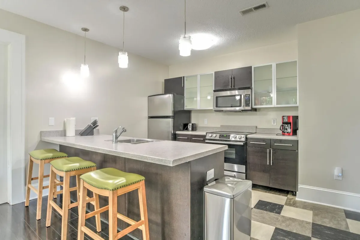 A modern kitchen island with stools, sleek appliances, and well-organized cabinetry. The open-plan layout connects the kitchen to the living space, creating a functional hub for cooking, casual dining, and entertaining.